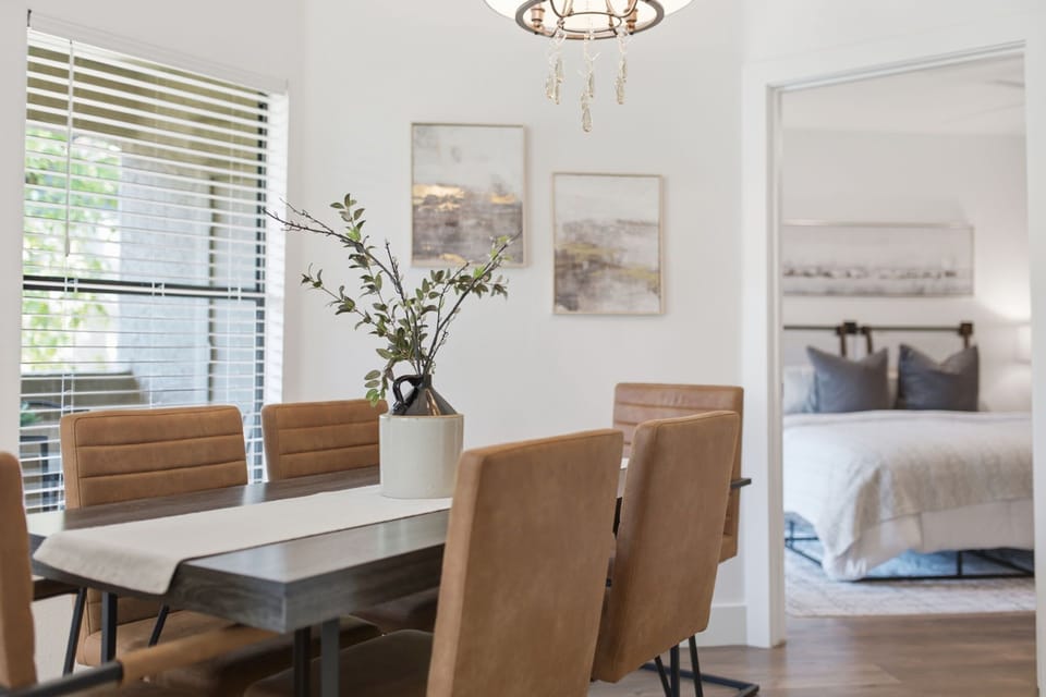 The dining room seats six around a sleek table beneath a crystal-drop chandelier, with a private patio door bringing in natural light.