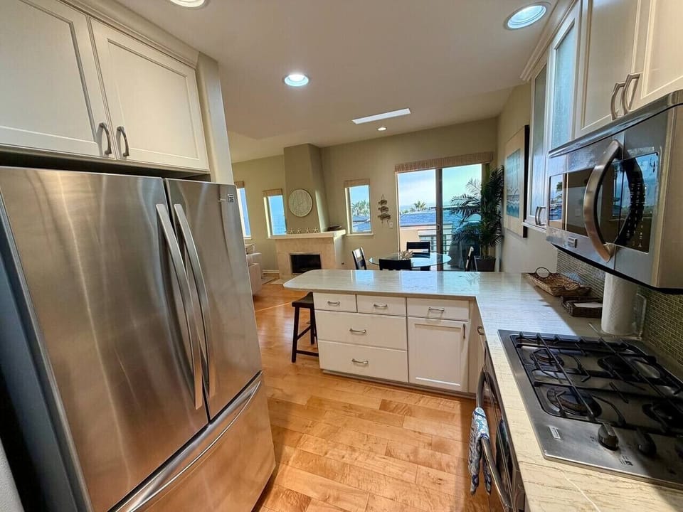 A fully equipped kitchen for real cooking, with a double-door refrigerator, four-burner gas range and oven, dishwasher, and microwave.