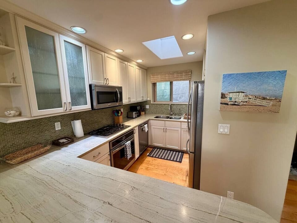 A fully equipped kitchen for real cooking, with a double-door refrigerator, four-burner gas range and oven, dishwasher, and microwave.