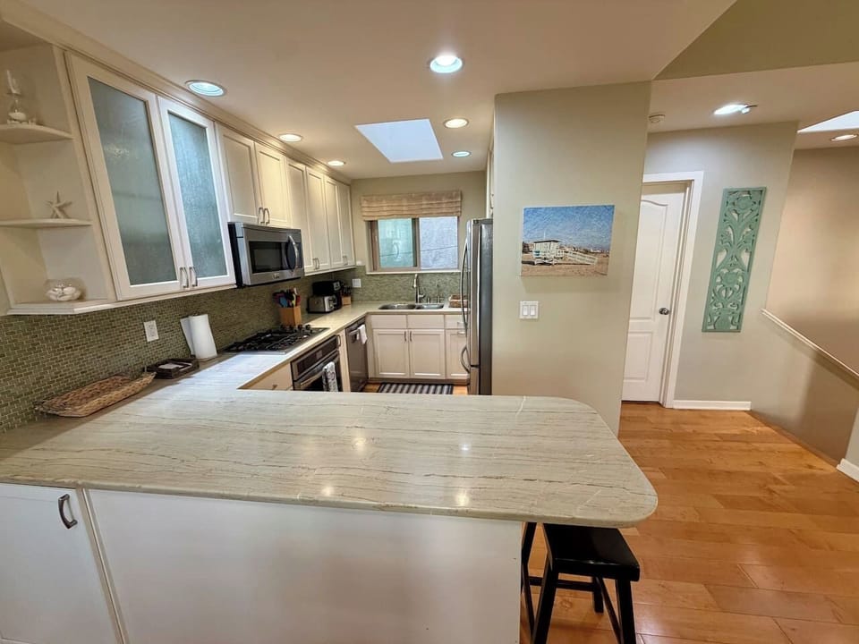 A fully equipped kitchen for real cooking, with a double-door refrigerator, four-burner gas range and oven, dishwasher, and microwave.