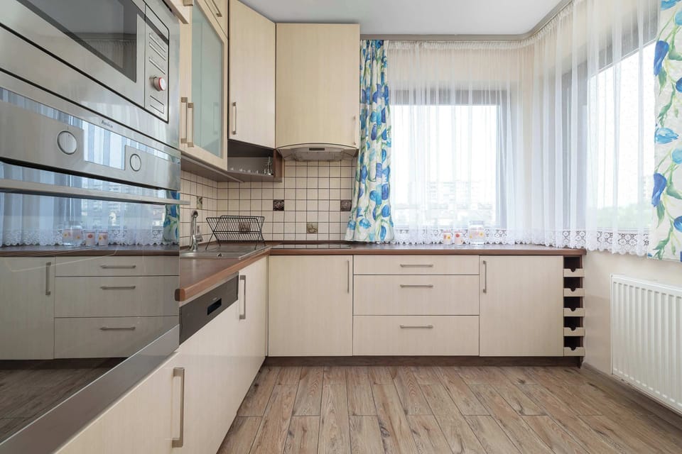 A bright kitchen with light-colored cabinets, modern appliances, and a large window. The practical layout provides plenty of space for preparing meals.
