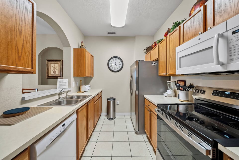 Welcome to this inviting kitchen with warm wood cabinetry and sleek stainless-steel appliances, perfect for meal prep together. The bright, tiled design encourages you to enjoy every moment in this functional culinary space.