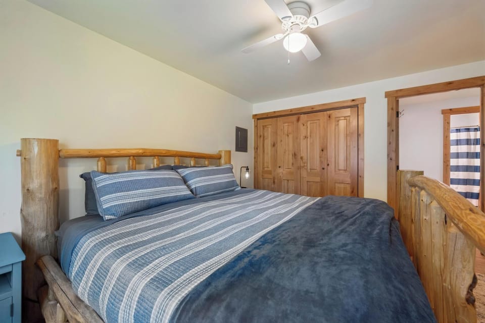 Sink into the handcrafted log bed wrapped in cozy striped linens. Rustic wood details and a ceiling fan create a peaceful mountain retreat for your restful nights.