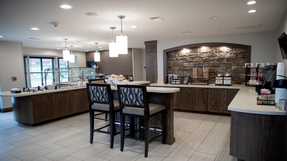 Breakfast counter with glass food display, beverage dispensers, and pendant lighting