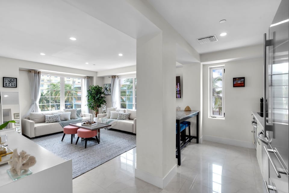 Sun-drenched open layout with polished floors and abundant windows — the living space connects effortlessly to the kitchen and bar area, creating a bright, airy home base for your South Beach getaway.