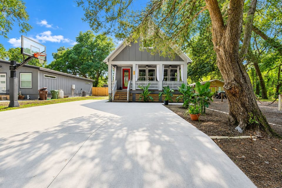Charming cottage with large driveway, porch, and peaceful tree-lined yard