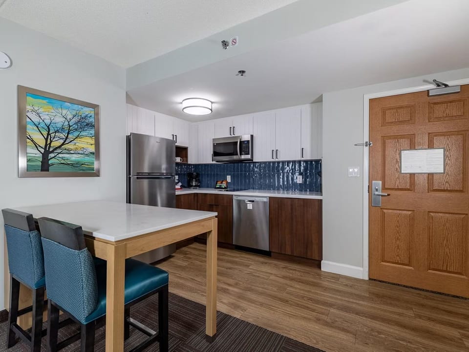 Dining table in the kitchen area comes with full-size appliances and a vibrant backsplash for meal prep.