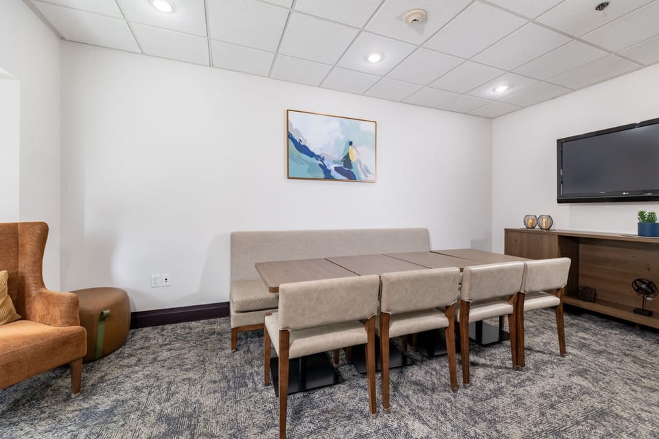 Private meeting room with long table, chairs, and wall-mounted television.