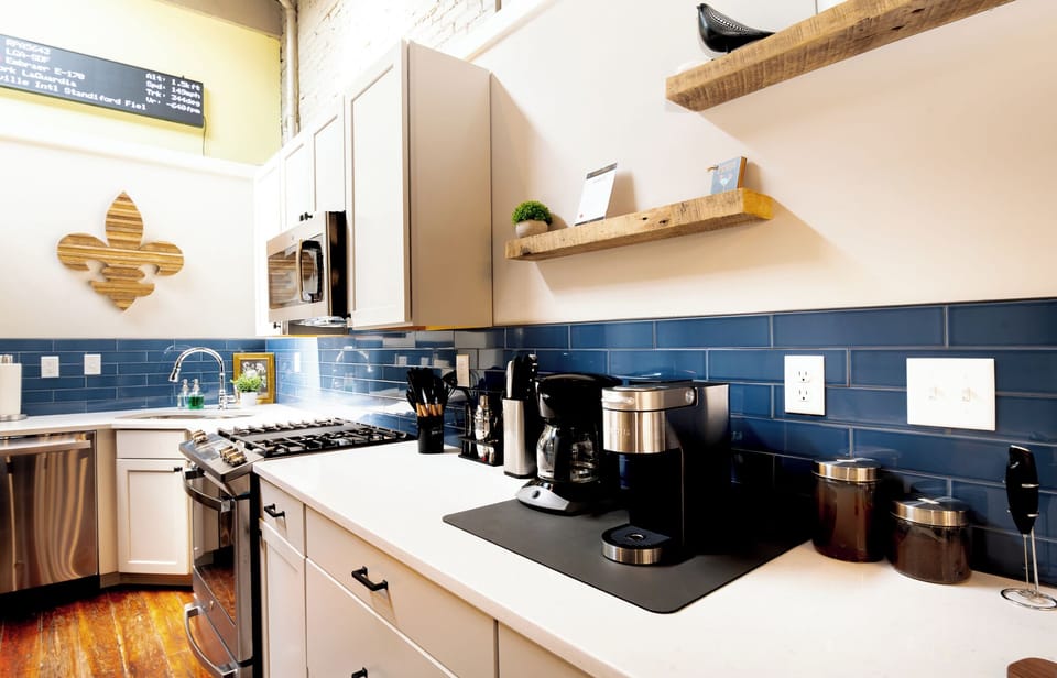 Brew a fresh cup of coffee at our fully stocked station in the beautiful modern kitchen. The deep blue subway tile looks amazing against the chunky wood shelves.
