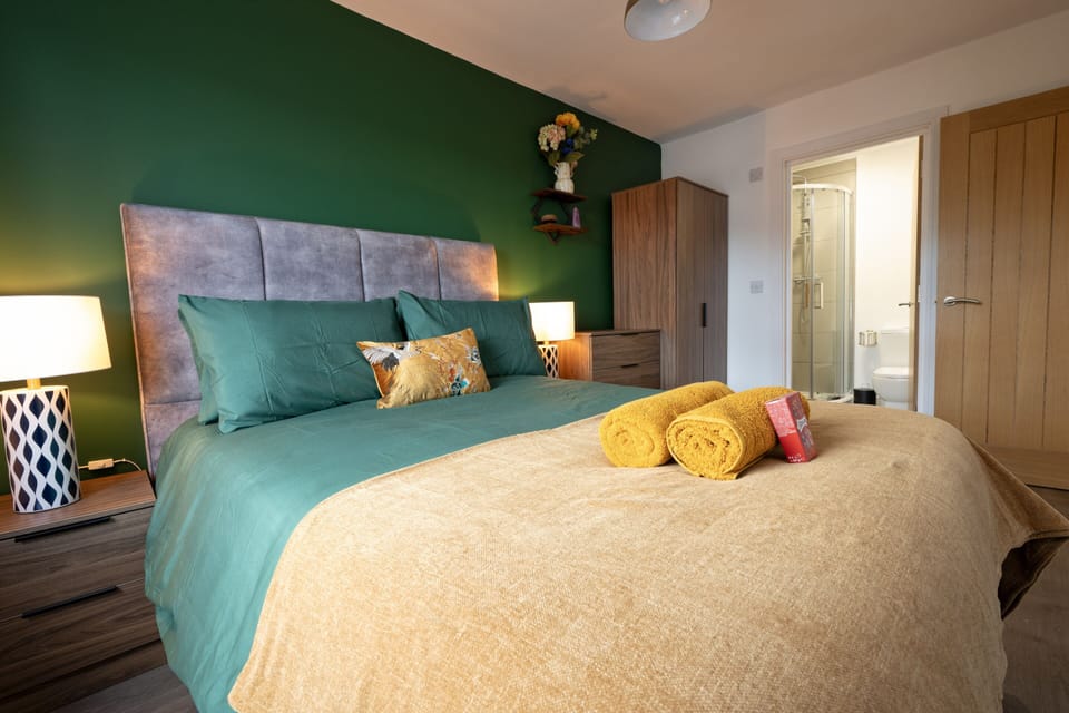 King bedroom with statement green wall and upholstered bed