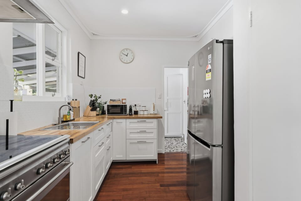 A bright, stylish kitchen featuring warm wooden countertops, sleek white cabinetry, and stainless steel appliances—perfect for preparing home-cooked meals during your stay.
