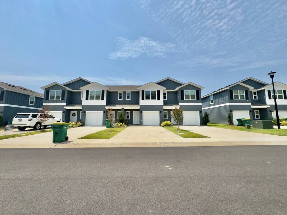 Modern townhome exterior featuring a clean coastal design, private garage, landscaped frontage, and a quiet residential setting.