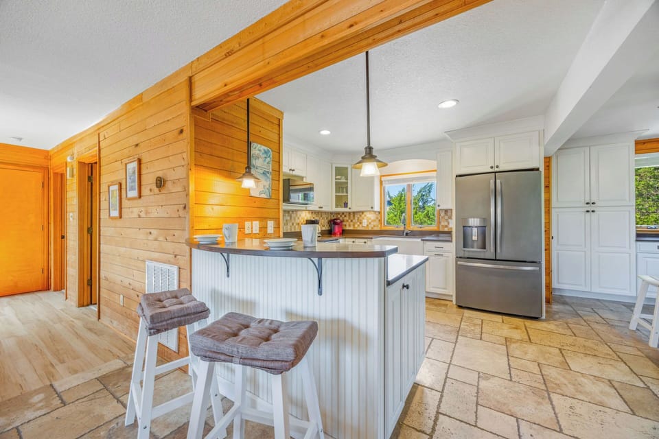 Your bright open-concept kitchen awaits with warm wood accents, modern appliances, and an inviting breakfast bar perfect for morning coffee or planning your daily adventures.
