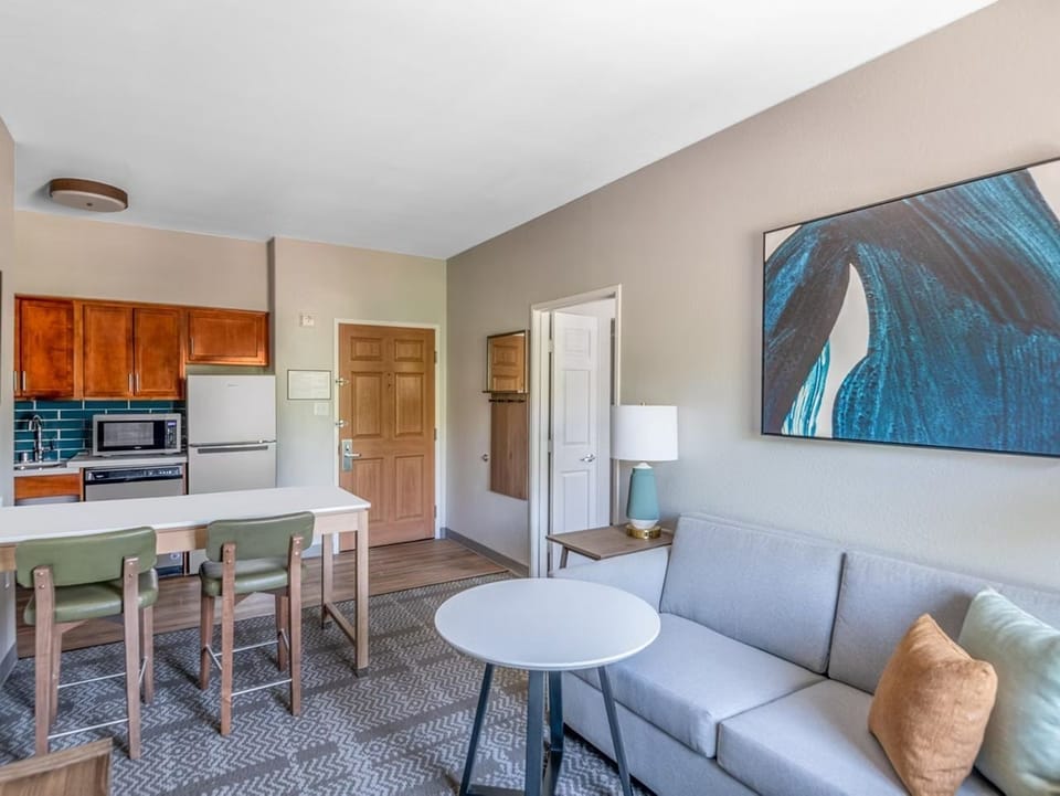 Kitchen, two-stool dining bar, and sofa visible from the entry — the full suite layout at a glance