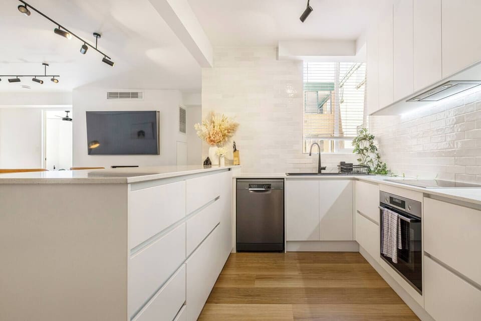 Cook comfortably in a sleek, fully equipped kitchen featuring an oven, stove, microwave, dishwasher, fridge, kettle, toaster, and generous bench space.