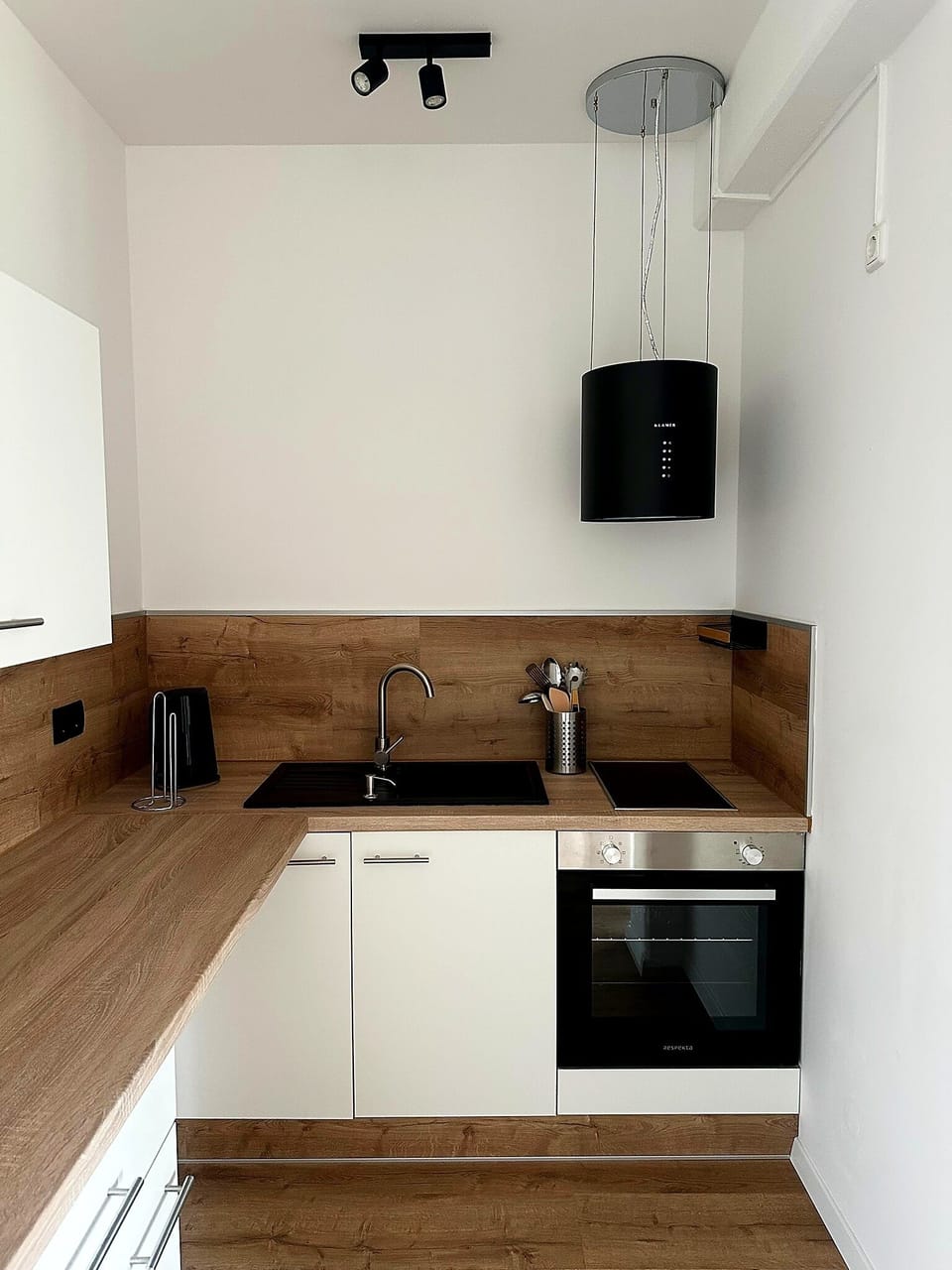 Modern kitchenette with wood accents, built-in oven, and sleek finishes