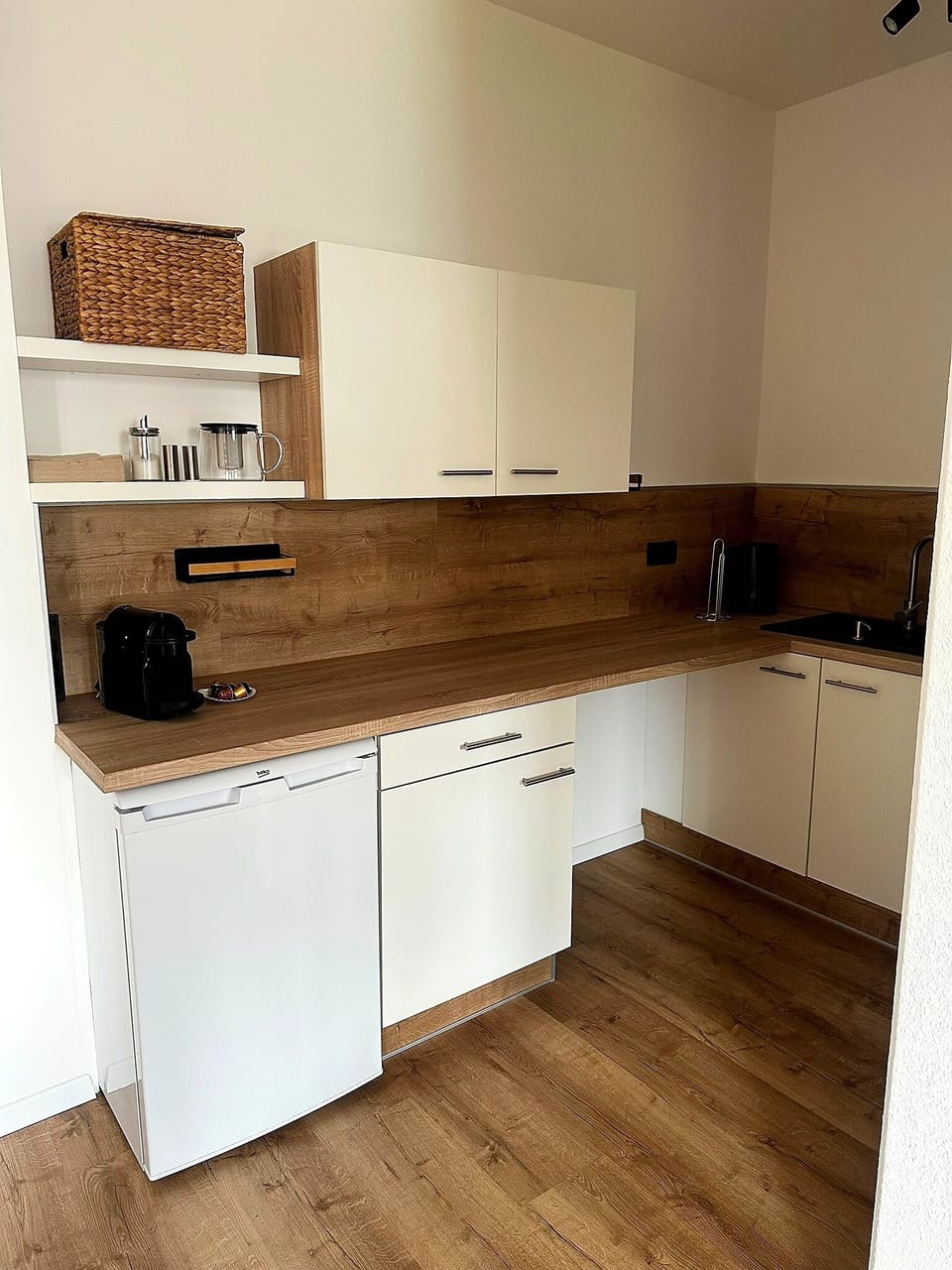 Modern kitchenette with wood accents, coffee station, and smart storage