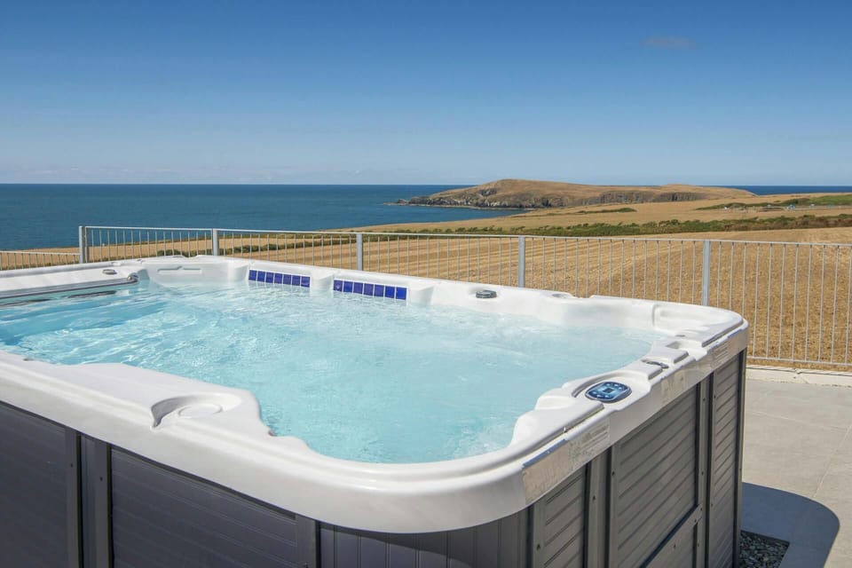 Outdoor hot tub on a patio overlooking the sea and coastline