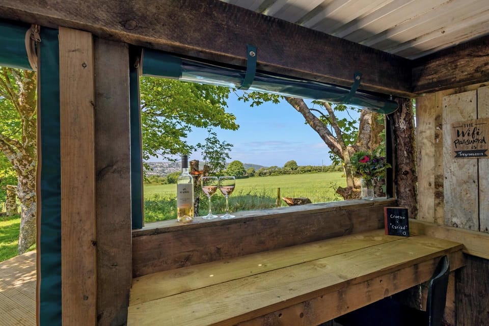 Rustic wooden bar counter by an open window overlooking green fields