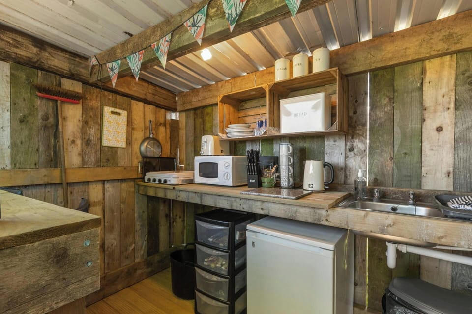 Small kitchen area with fridge, microwave, kettle and stainless-steel sink