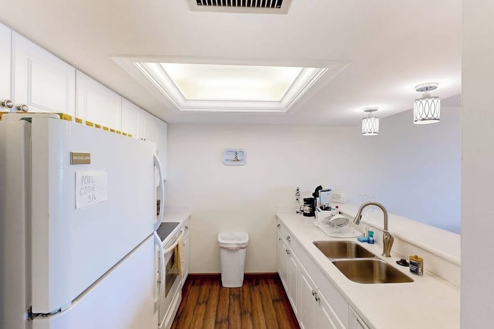 Fully stocked kitchen includes electric range, stovetop, refrigerator and freezer, dishwasher, microwave, and double basin sink.