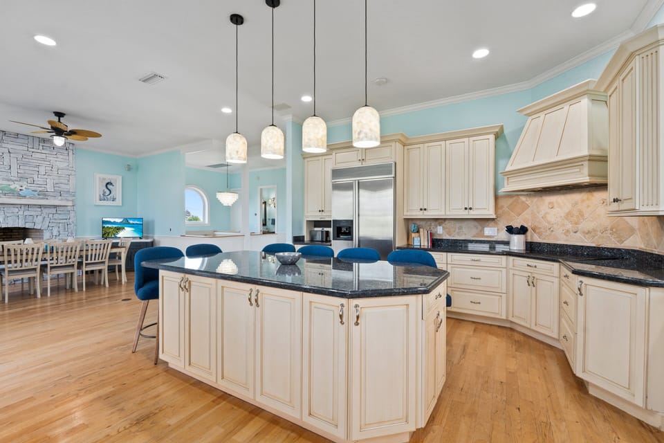 The kitchen features a large island with seating, stainless steel appliances, and a 3rd-floor balcony view of the Indian River Lagoon.