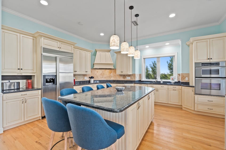 The kitchen features a large island with seating, stainless steel appliances, and a 3rd floor balcony view of sunsets over the Indian River Lagoon.