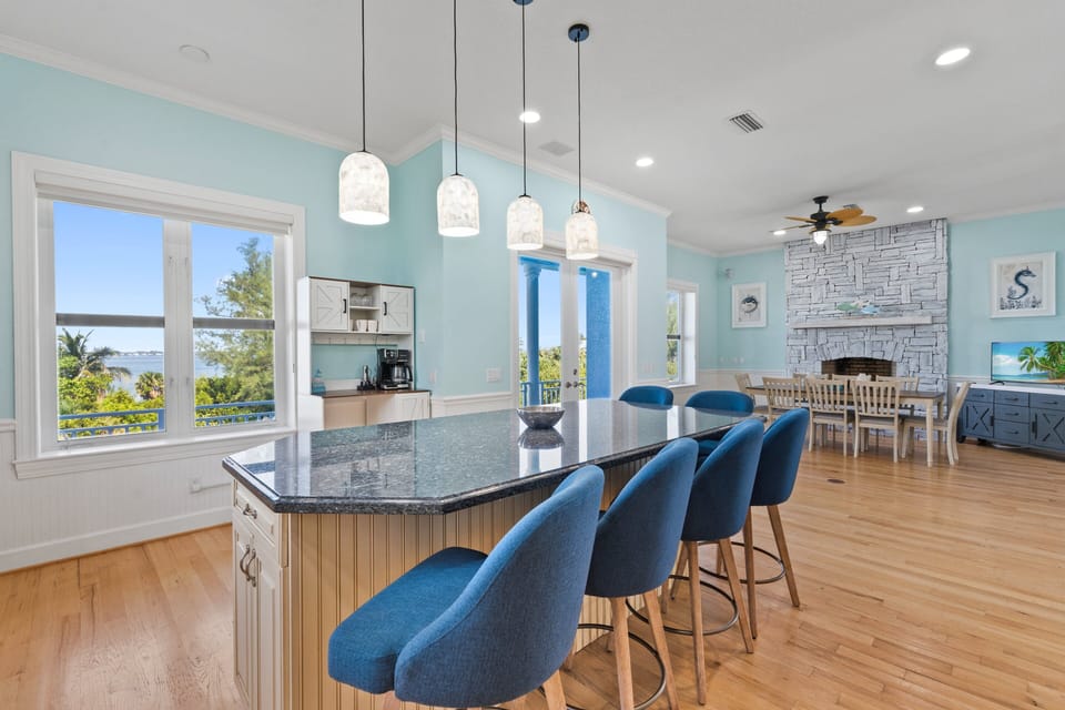The kitchen features a large island with seating, stainless steel appliances, and a 3rd-floor balcony view of the Indian River Lagoon.