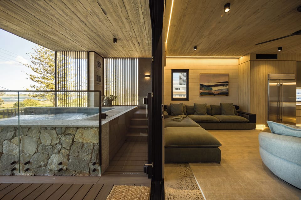 A carpeted bedroom with a leather bench seat and a bathroom alongside