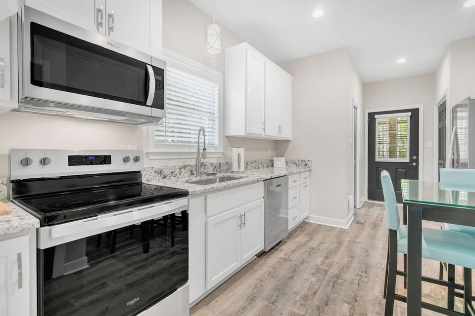 Full kitchen equipped for cooking with pots, pans, plates, glasses, silverware, cooking utensils, and baking dishes.
