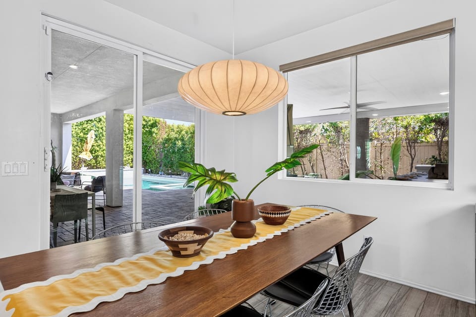 Elegant dining table set with decorative greenery and natural light from large windows.