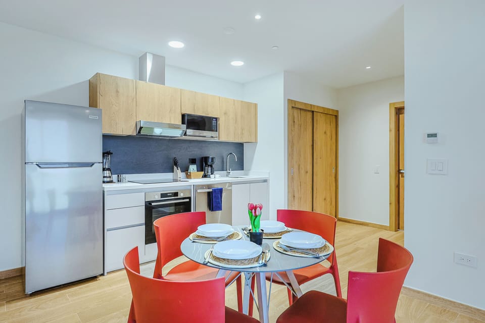 Step into your fully equipped modern kitchen and dining space, where bright natural light and sleek appliances invite you to prepare meals and gather around the cheerful table with ease.