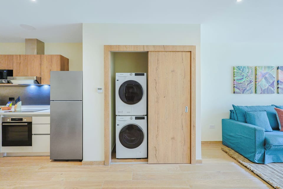 Your in-unit washer and dryer tucked neatly into this alcove makes laundry effortless, while the open-plan kitchen and vibrant living space keep your stay convenient and comfortable.