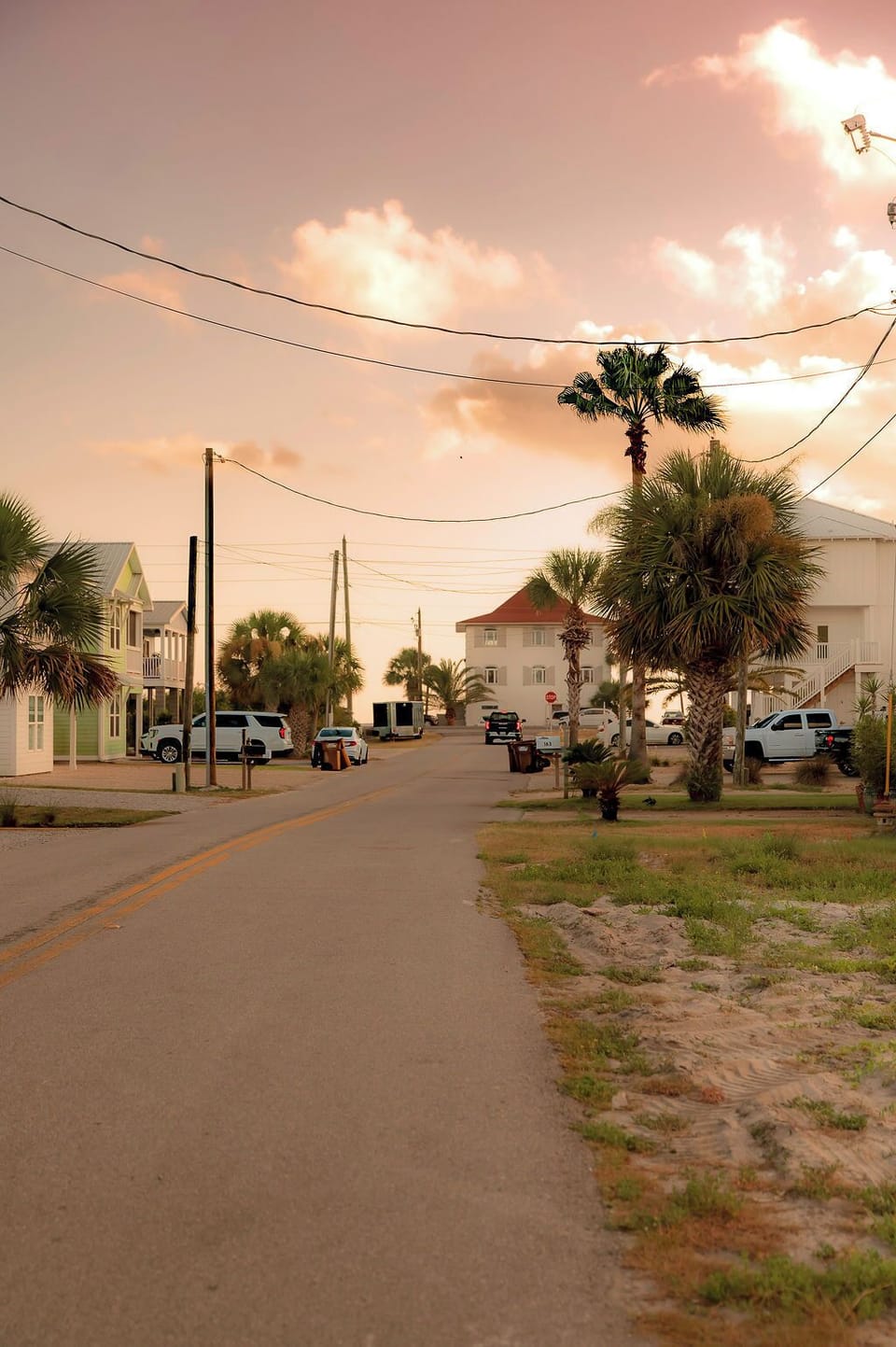 Quiet palm-lined beach street glowing under a beautiful sunset sky