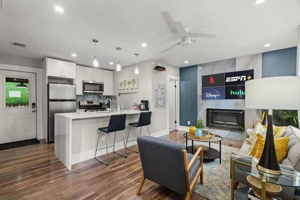 The open kitchen and living area flow together around a quartz island, smart TV, and cozy fireplace for easy hangouts.