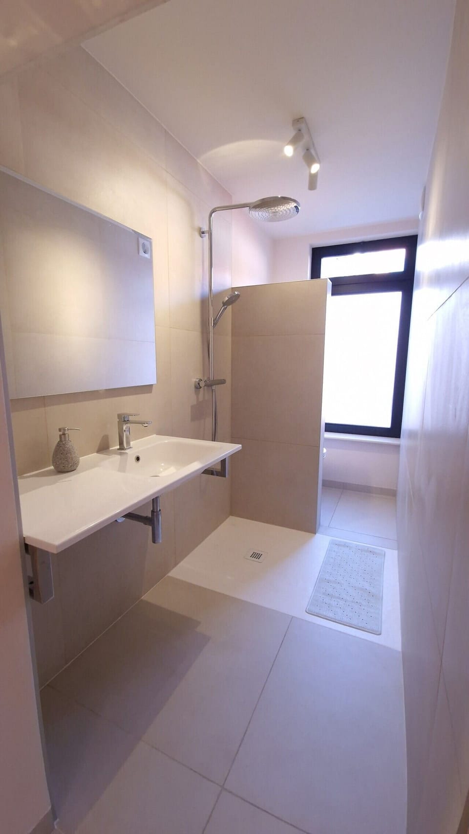 The en-suite bathroom, all yours: walk-in rain shower, washbasin and toilet, with shampoo and body wash provided.