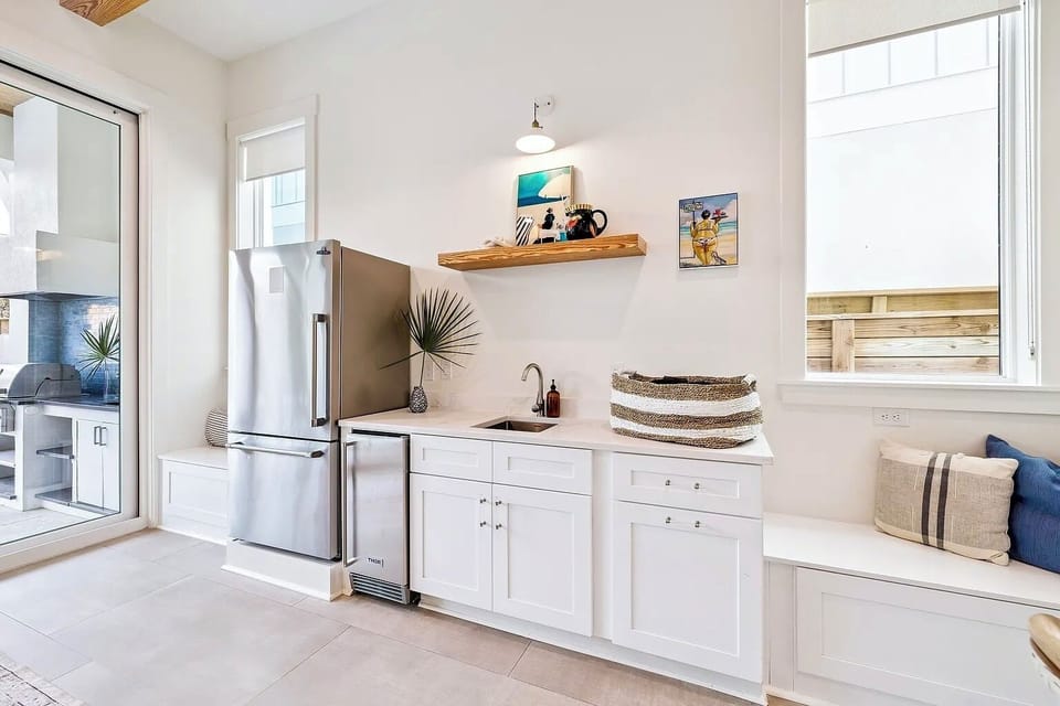 1st-floor refreshment station complete with beverage fridge, stainless steel sink, and built-in bench seating.