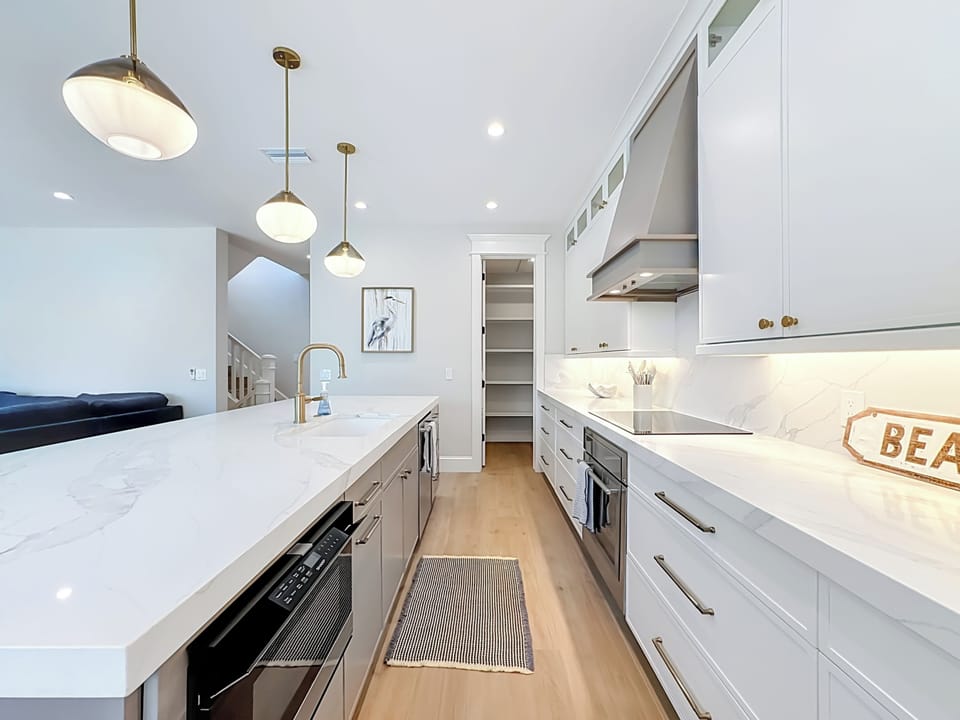 Step into your dream kitchen, with gleaming white counters, custom cabinetry, and modern pendant lights setting the scene for your culinary adventures.