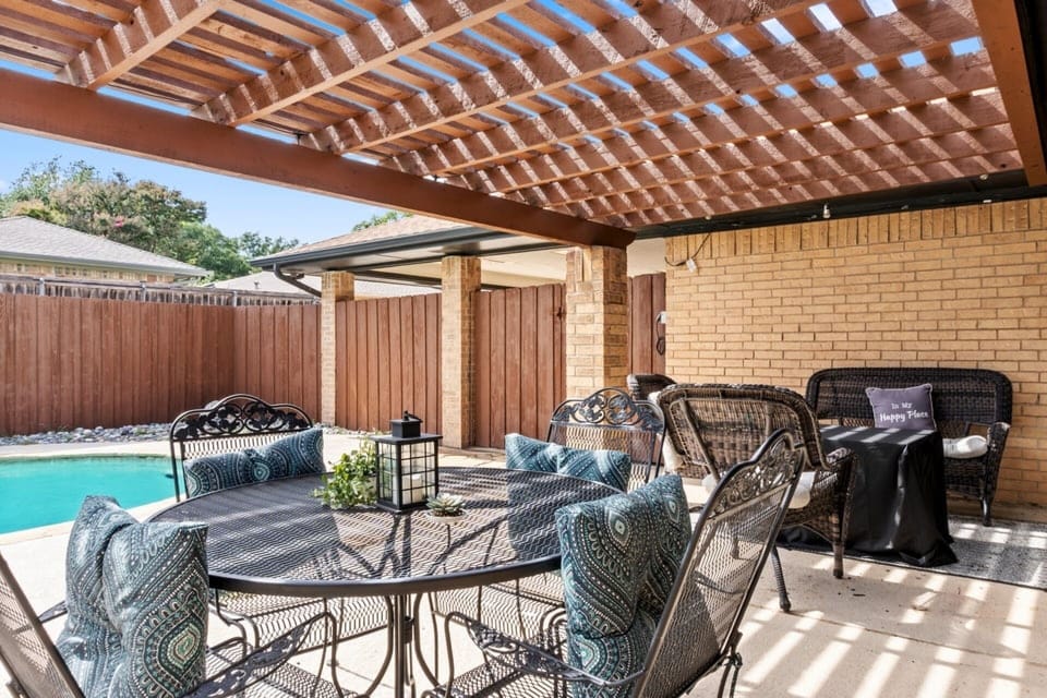 Gather for outdoor meals and evening conversations beneath the covered patio beside the pool.