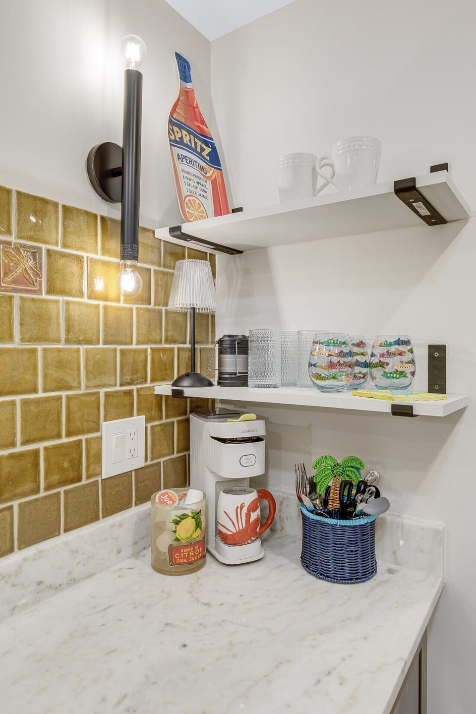 Coffee station setup featuring a single-serve coffee maker, drinkware, and wall-mounted shelving.