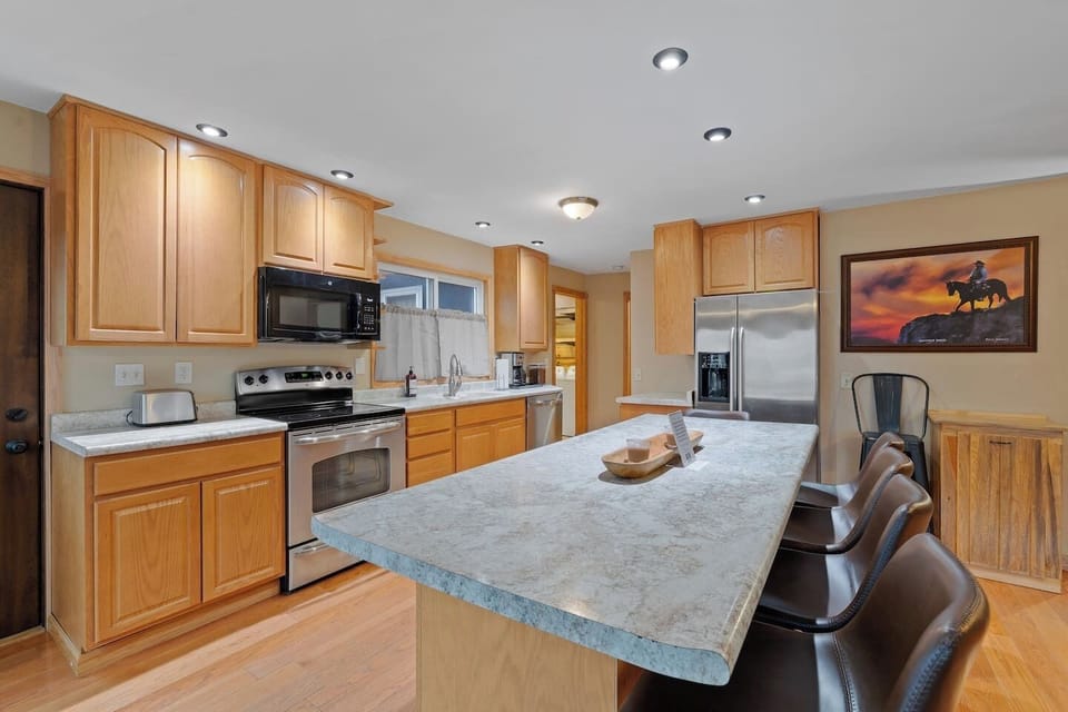 A spacious, fully equipped kitchen featuring modern appliances, ample cabinetry, and a large island with plenty of seating for dining and gathering.