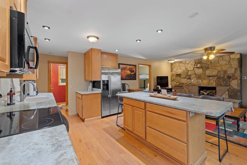 A well-equipped kitchen with generous counter space, a large island with seating, modern appliances, and an open view into the cozy living area.