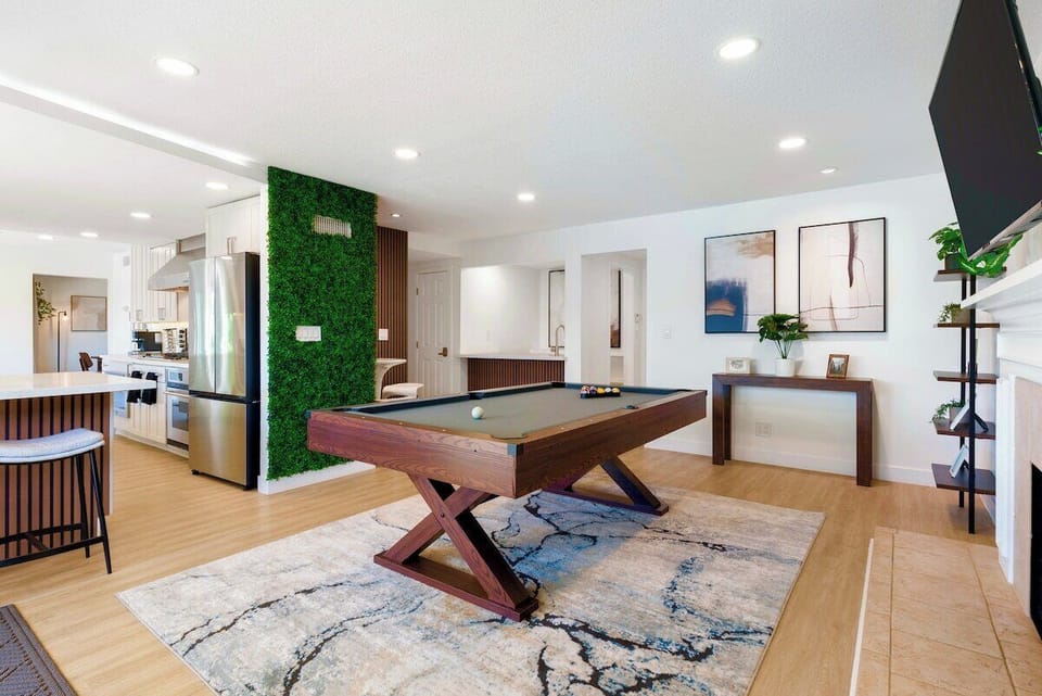 Open-concept recreation area centered on a billiards table, that seamlessly blend into the adjacent kitchen and living space.