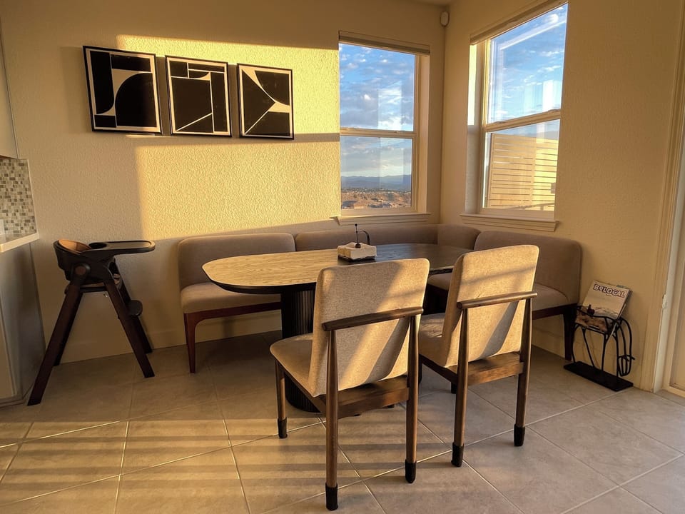 Dine with a view. This inviting dinning space features comfortable booth seating, modern mid-century chairs, and large windows showcasing stunning scenic vistas. The perfect sun-drenched spot to enjoy breakfast or a family dinner.