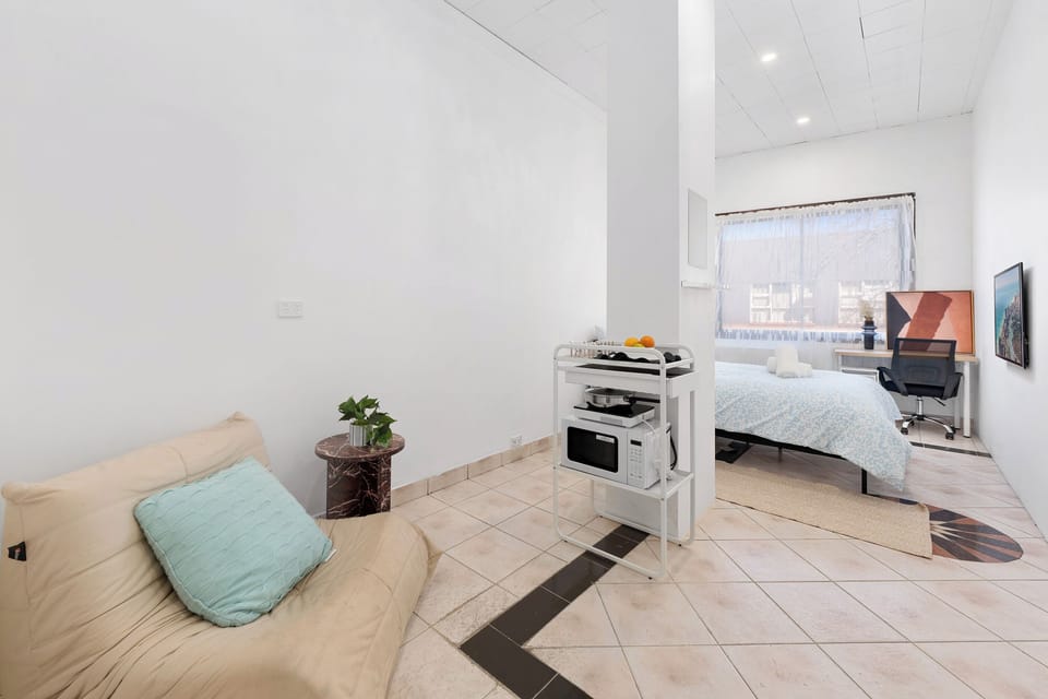 Bright open-plan studio with workspace, TV, and cozy lounge corner