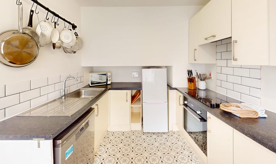 The galley kitchen runs the length of the room, with pans hung on a rail overhead. Fridge, dishwasher and microwave all within a step or two.