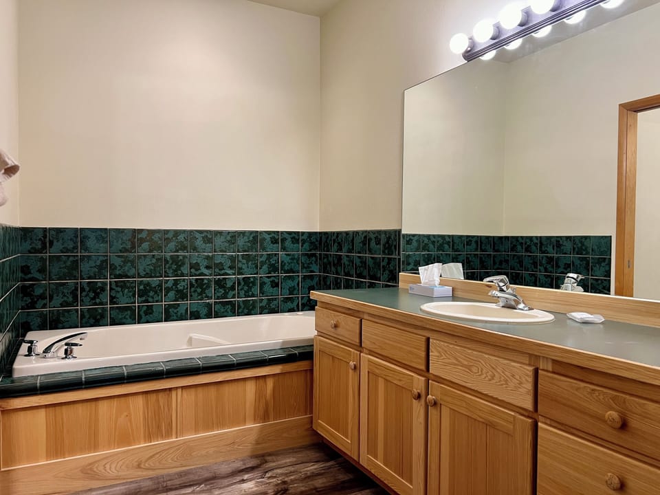 Spacious bathroom with soaking tub, large vanity, and warm cabin-style finishes