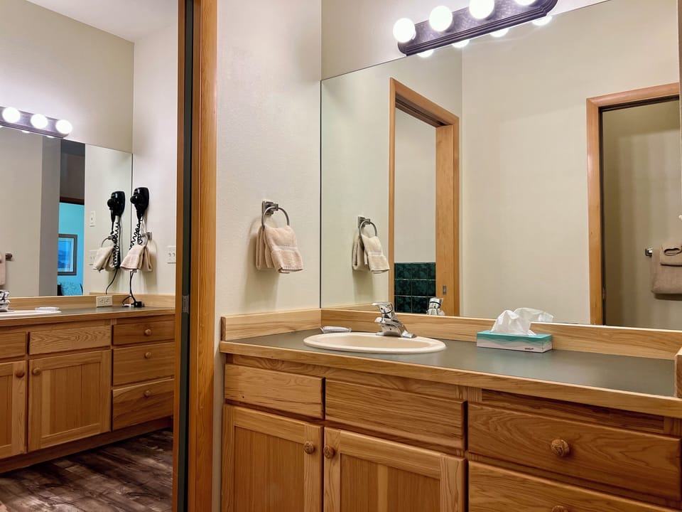 Bright bathroom vanity with large mirror, warm wood finishes, and guest-ready touches
