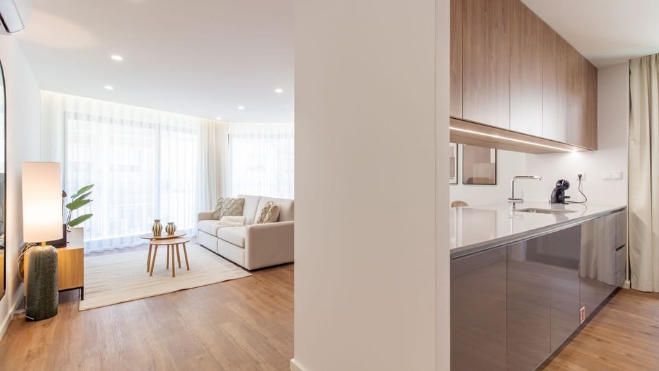 Step into a beautifully designed space where the inviting living room flows effortlessly into the modern kitchen, offering both comfort and convenience for your stay. The blend of warm wood tones and bright whites creates a welcoming and sophisticated atm