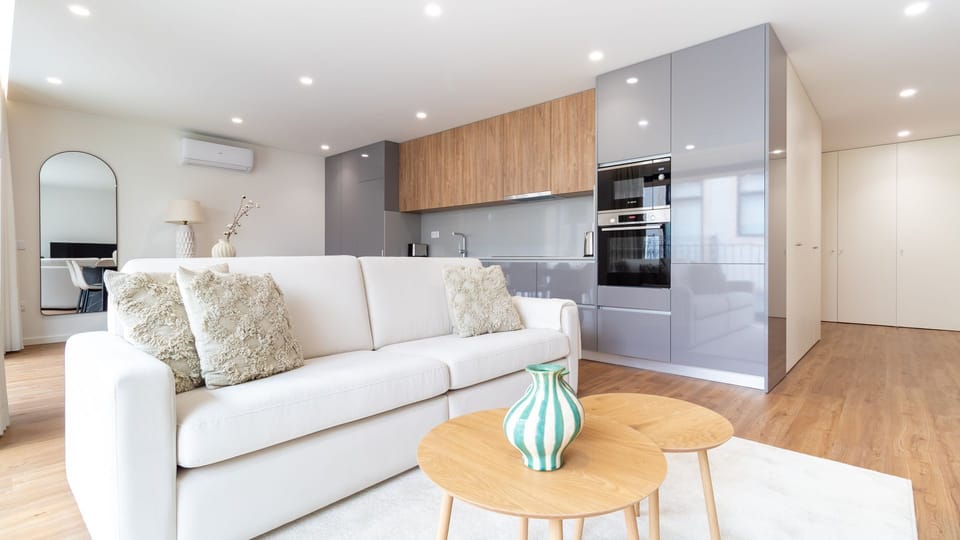 Experience seamless open-concept living, where a plush sofa invites you to relax while the sleek, fully equipped kitchen stands ready for culinary adventures. This space is designed for both socializing and quiet comfort, blending functionality with conte